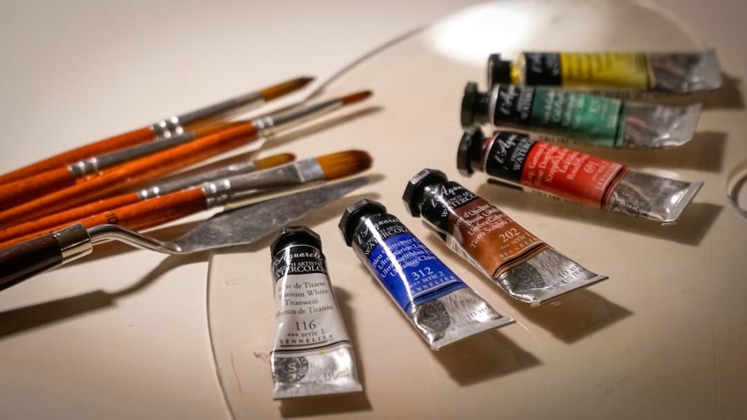 Akvarellfärgtuber och penslar i varmt ljus